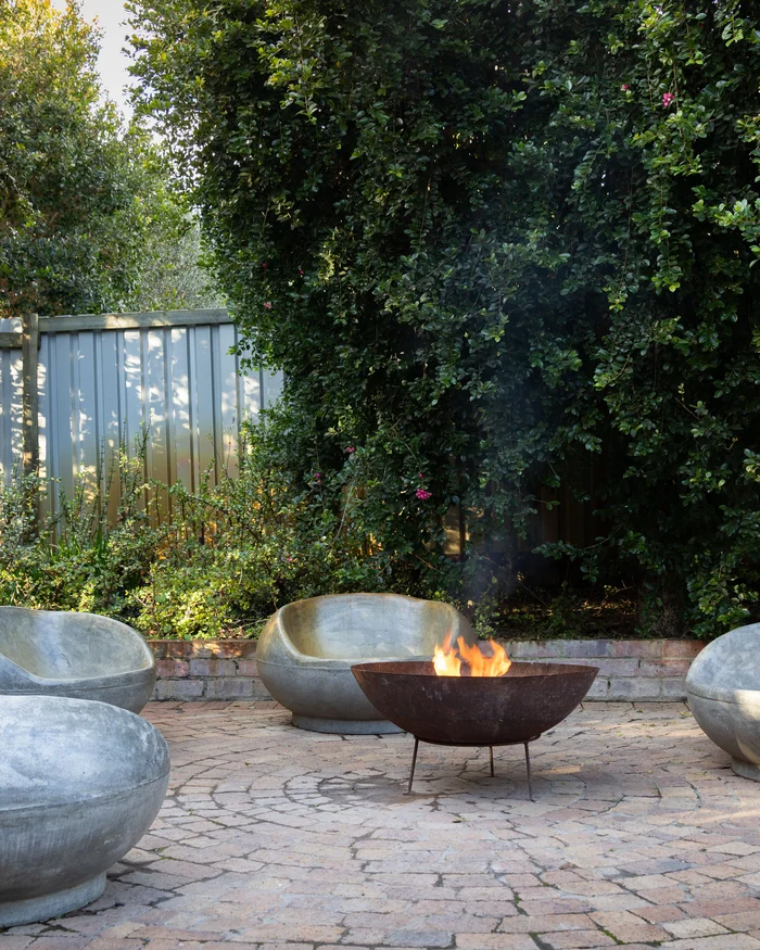 Circular paver patio with a fire pit, stone seats and a low block seating wall