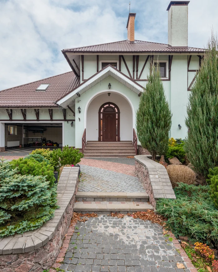 Stone paver walkway and steps leading up to an arched front door